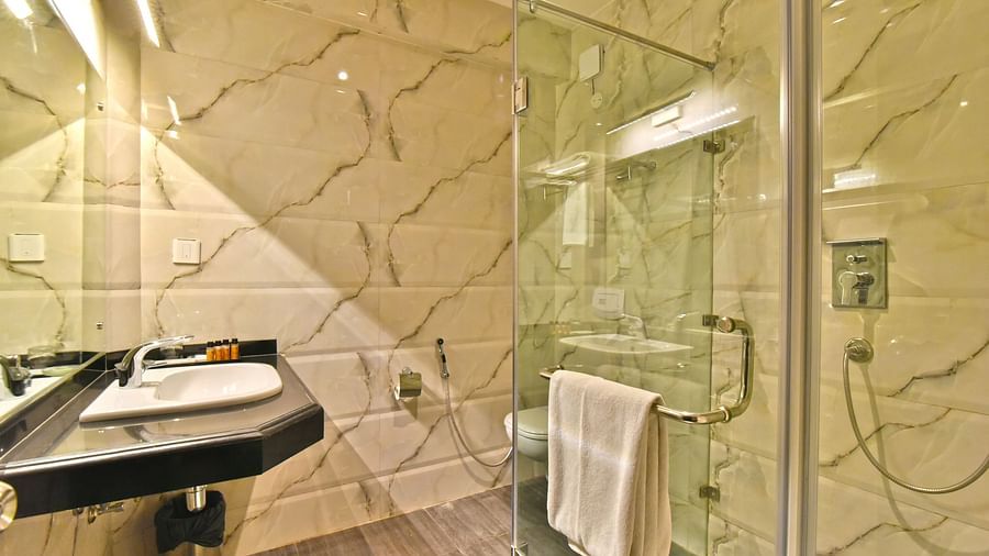 A shower cubicle with a wash basin beside it at DLS Hillcrest Resort, Shimla.